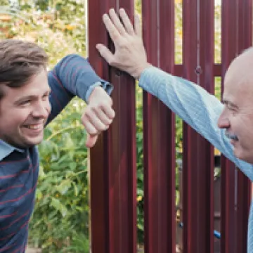 Foto: Zwei Nachbarn unterhalten sich am Gartenzaun