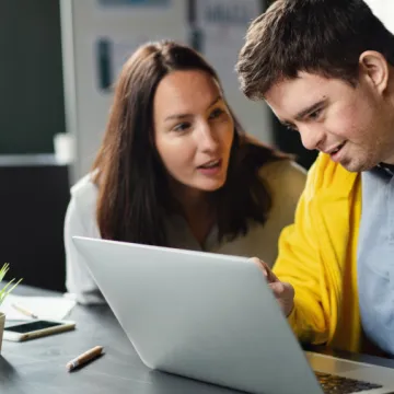 Drei Menschen im Büro - darunter ein Mann mit Behinderung