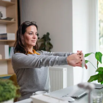 Frau im Home-Office macht Entspannungsübung