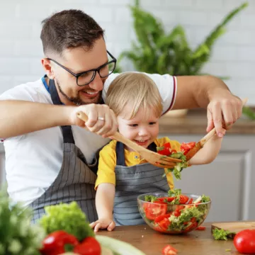 Mann und Kind bereiten einen Salat zu
