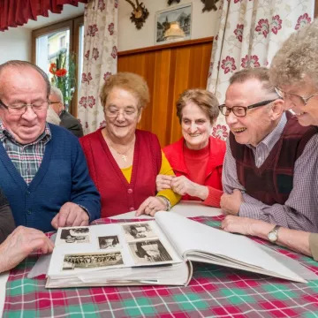 Seniorinnen und Senioren blättern in Fotoalbum 