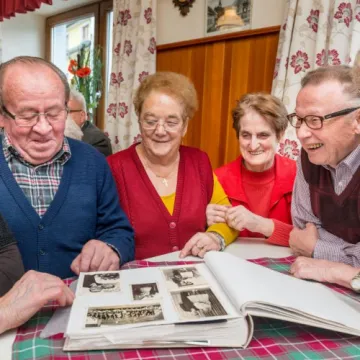 Ältere Personen schauen sich ein Fotoalbum an
