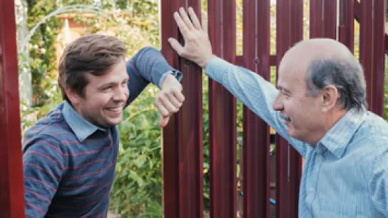Foto: Zwei Nachbarn unterhalten sich am Gartenzaun