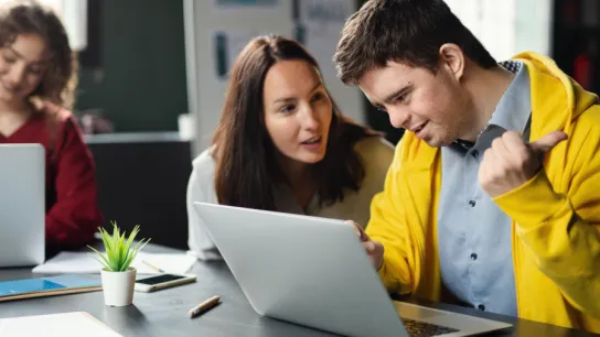Drei Menschen im Büro - darunter ein Mann mit Behinderung
