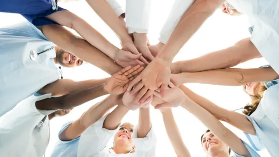 Medizinische Fachkräfte legen ihre Hände sternförmig zusammen