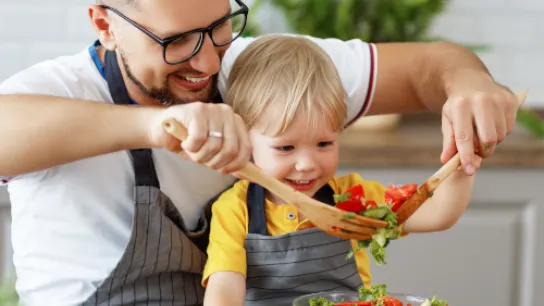 Mann und Kind bereiten einen Salat zu