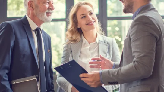Älterer Mann mit zwei jüngeren Mitarbeitern im Büro