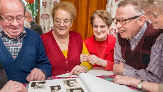 Seniorinnen und Senioren blättern in Fotoalbum 