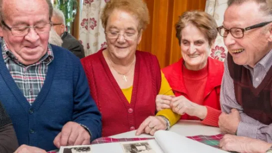 © Kerschbaum Ältere Personen schauen sich ein Fotoalbum an